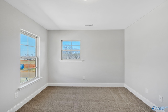 carpeted spare room with visible vents and baseboards