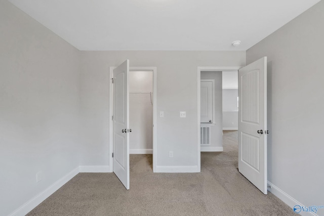 unfurnished bedroom with visible vents, baseboards, a closet, carpet, and a walk in closet