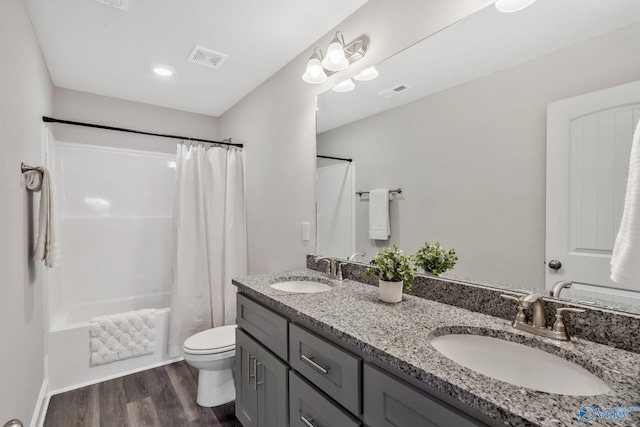 bathroom featuring toilet, visible vents, a sink, and wood finished floors