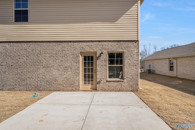 exterior space featuring central air condition unit, brick siding, and a patio