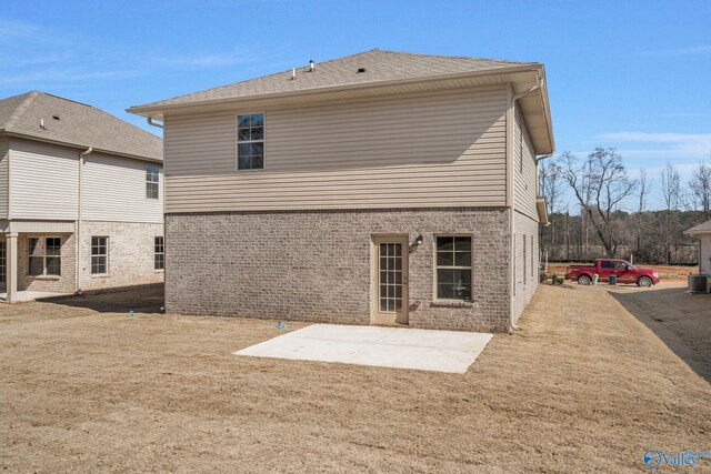 back of property with cooling unit, a patio area, and brick siding