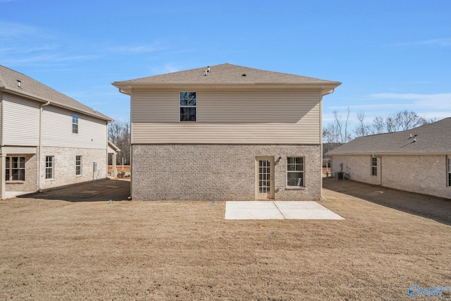 rear view of property featuring central air condition unit, a yard, a patio, and brick siding