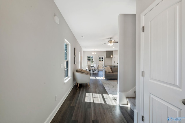 hall featuring an inviting chandelier, stairs, baseboards, and wood finished floors