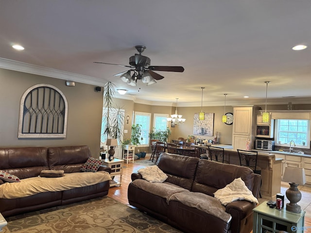 living room featuring ornamental molding, ceiling fan with notable chandelier, light wood-type flooring, and recessed lighting