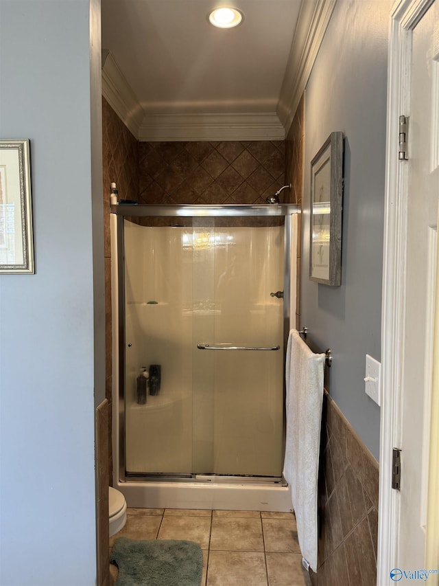 bathroom with tile patterned floors, crown molding, toilet, and a shower stall