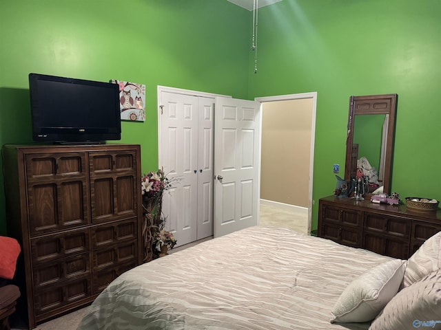 bedroom featuring baseboards, a high ceiling, a closet, and carpet