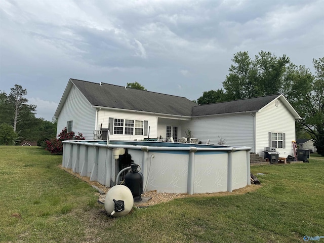 rear view of property with a yard and an outdoor pool