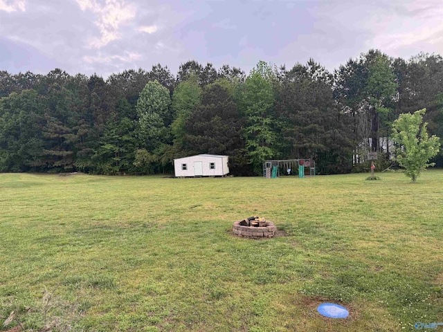 view of yard with an outdoor fire pit, a storage shed, and an outbuilding