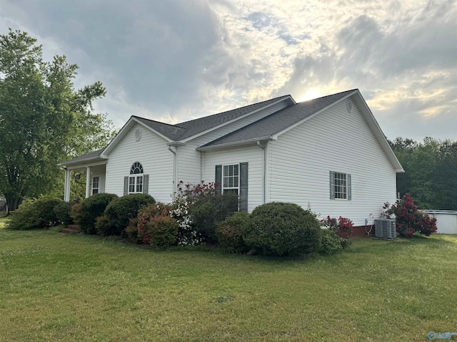 view of property exterior with a yard, roof with shingles, and central AC unit