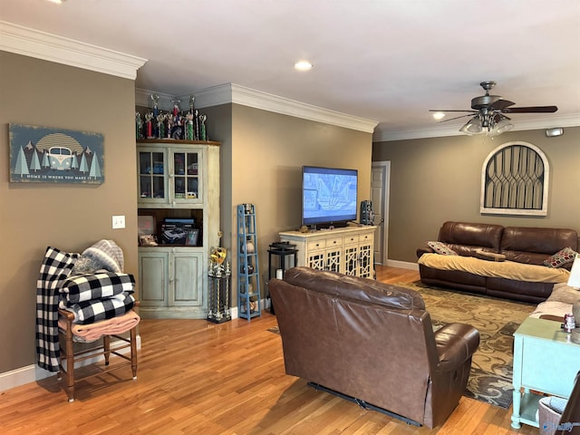 living area with crown molding, wood finished floors, baseboards, and ceiling fan