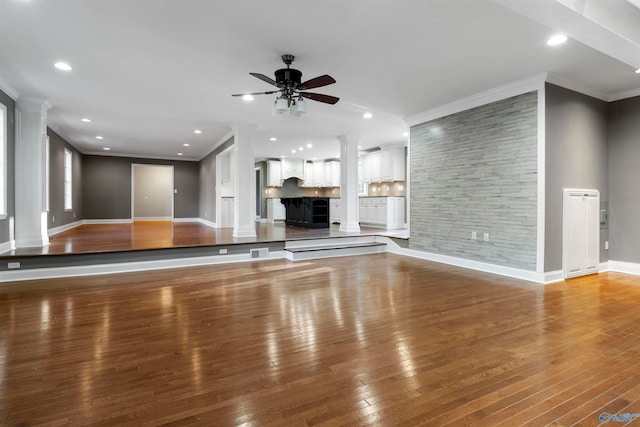 unfurnished living room featuring hardwood / wood-style flooring, ceiling fan, and crown molding