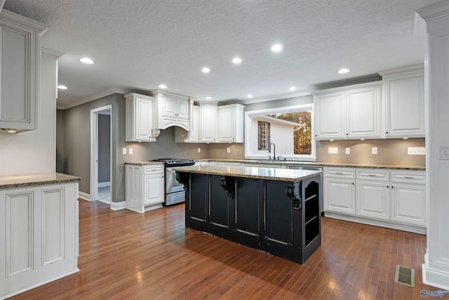 kitchen featuring a textured ceiling, white cabinetry, stainless steel range with gas cooktop, and dark wood-type flooring