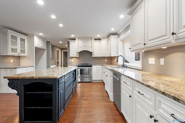 kitchen featuring appliances with stainless steel finishes, hardwood / wood-style flooring, white cabinetry, and light stone counters