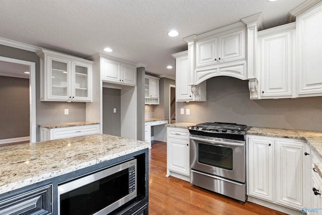 kitchen featuring hardwood / wood-style floors, crown molding, white cabinetry, and stainless steel appliances