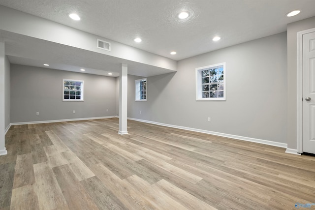 basement with light hardwood / wood-style flooring and a textured ceiling