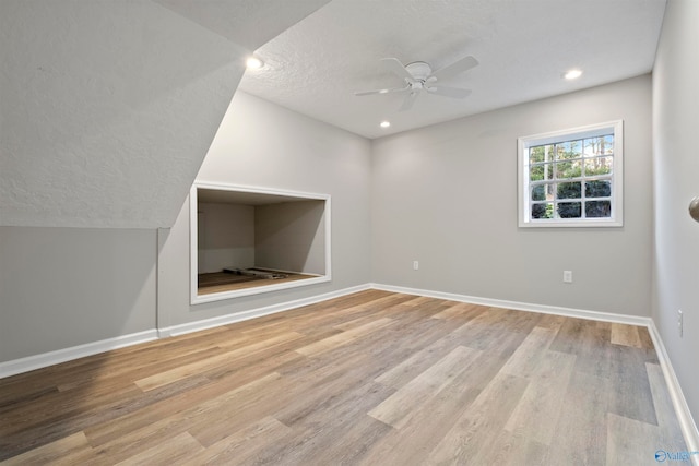 additional living space featuring ceiling fan, a textured ceiling, and light wood-type flooring