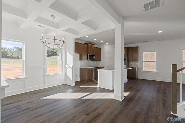 kitchen featuring a kitchen island, beamed ceiling, dark wood-type flooring, a chandelier, and backsplash