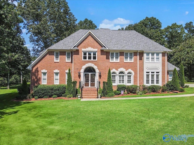 view of front of home featuring brick siding, french doors, a shingled roof, and a front lawn