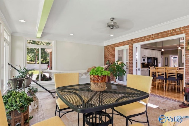 dining space featuring light tile patterned flooring, brick wall, a ceiling fan, and ornamental molding