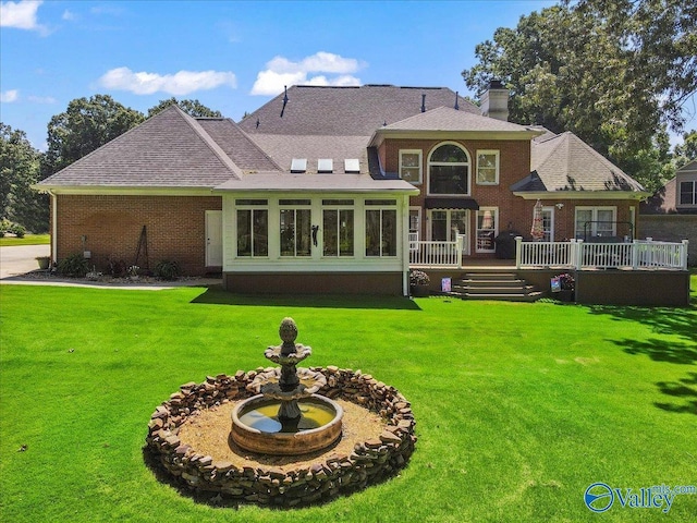 back of property with a wooden deck, a lawn, a chimney, and a shingled roof