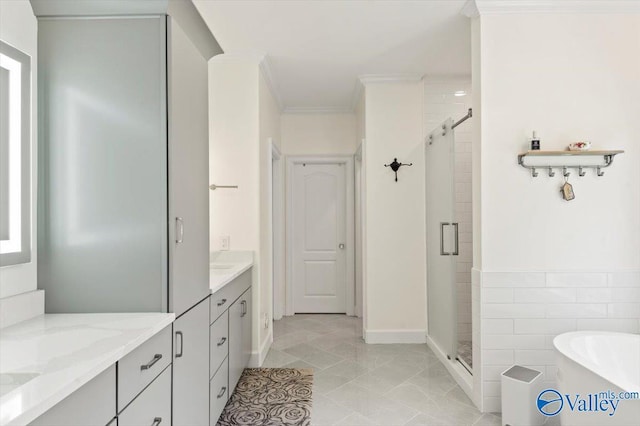bathroom with tile walls, ornamental molding, a stall shower, a soaking tub, and vanity