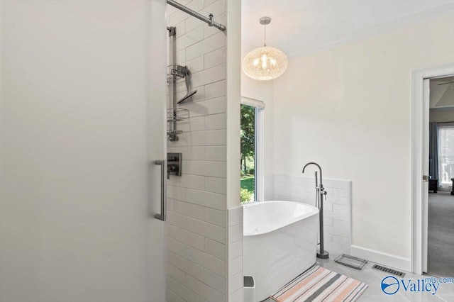full bathroom featuring a freestanding tub, a notable chandelier, tile patterned flooring, and a tile shower