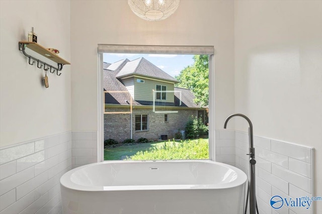 full bath with a freestanding bath, tile walls, and wainscoting