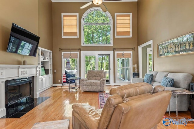 living room with a fireplace, plenty of natural light, wood finished floors, and ceiling fan