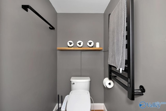 half bath featuring toilet and baseboards