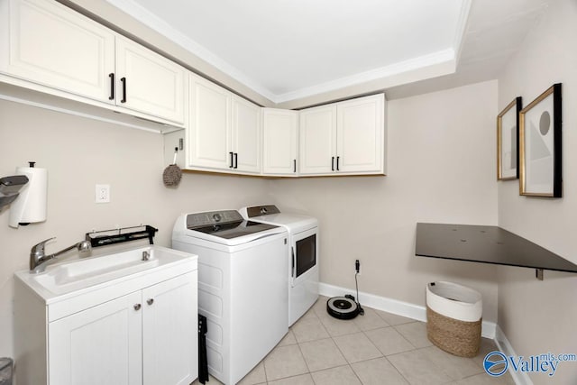 laundry area with washing machine and clothes dryer, a sink, light tile patterned flooring, baseboards, and cabinet space