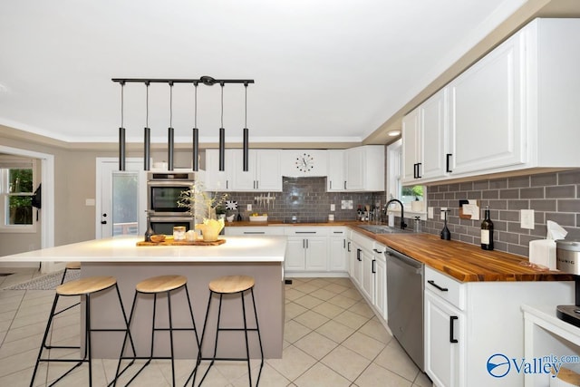 kitchen featuring tasteful backsplash, a sink, wooden counters, a breakfast bar, and stainless steel appliances