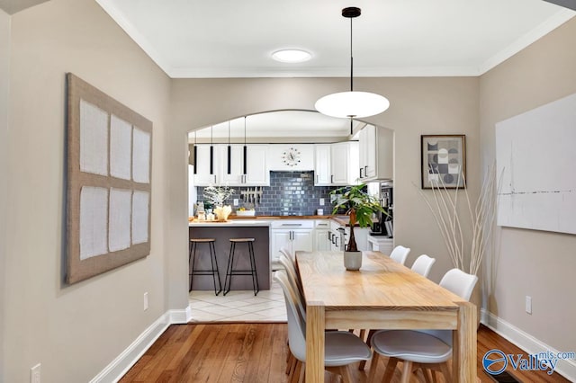 dining room with light wood-style floors, baseboards, and ornamental molding