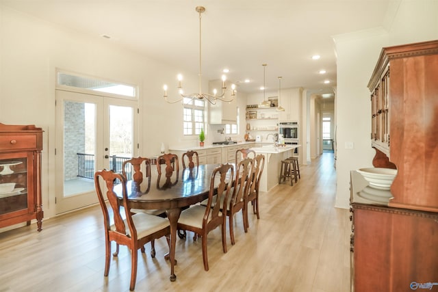 dining space featuring light wood-type flooring, french doors, a chandelier, and sink