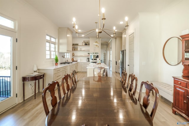 dining area with ornamental molding, light hardwood / wood-style flooring, and an inviting chandelier