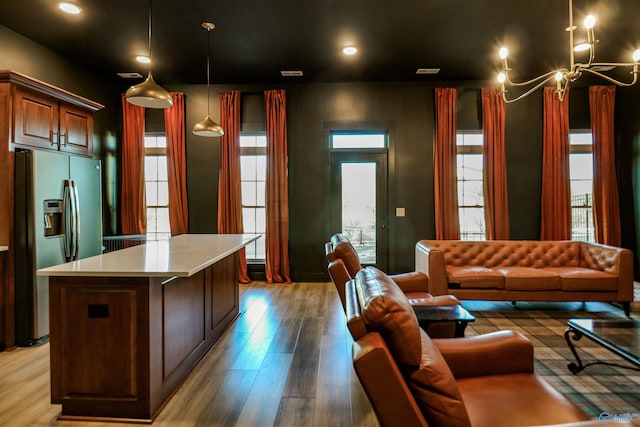 kitchen with light hardwood / wood-style floors, hanging light fixtures, a center island, a notable chandelier, and stainless steel refrigerator with ice dispenser