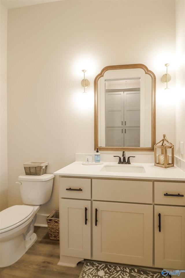 bathroom with toilet, vanity, and hardwood / wood-style floors