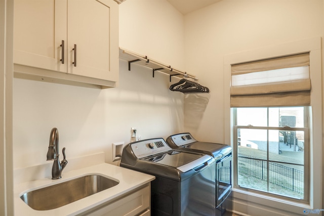 clothes washing area with sink, a healthy amount of sunlight, cabinets, and washer and clothes dryer