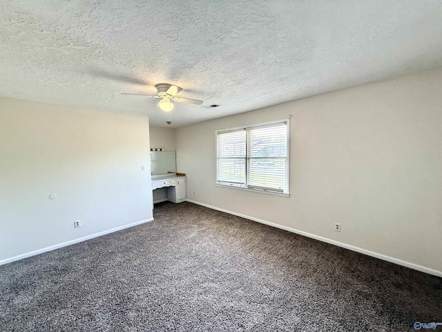 interior space with baseboards, a textured ceiling, visible vents, dark carpet, and ceiling fan