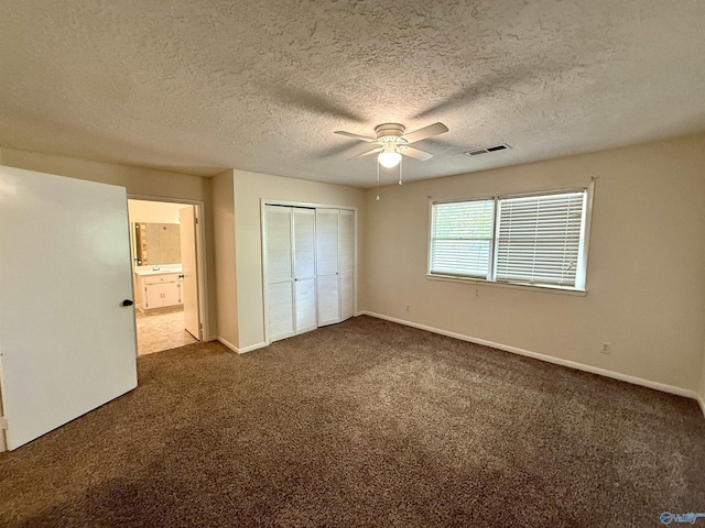 unfurnished bedroom with visible vents, baseboards, a closet, dark carpet, and a textured ceiling