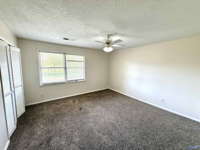 unfurnished bedroom featuring visible vents, baseboards, a closet, dark colored carpet, and a ceiling fan