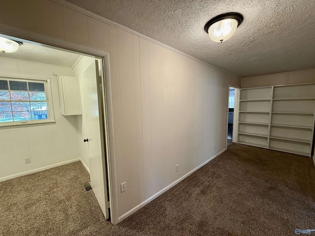 corridor featuring carpet, a textured ceiling, baseboards, and crown molding