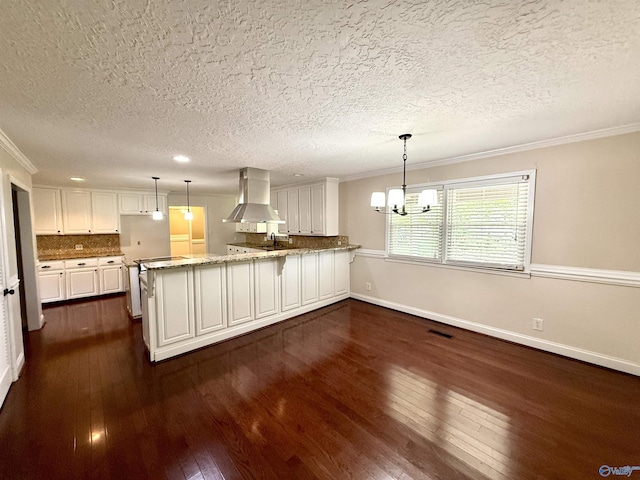 kitchen featuring dark wood-type flooring, a textured ceiling, ventilation hood, and a peninsula