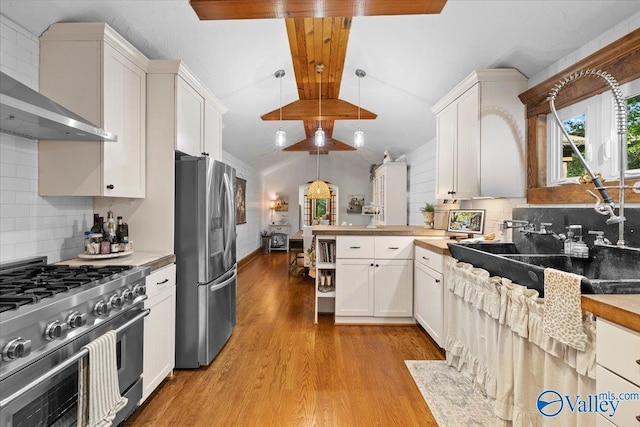 10161 US Highway 11, Springville, AL 35146 - kitchen featuring appliances with stainless steel finishes, wall chimney exhaust hood, a peninsula, lofted ceiling, and light wood finished floors
