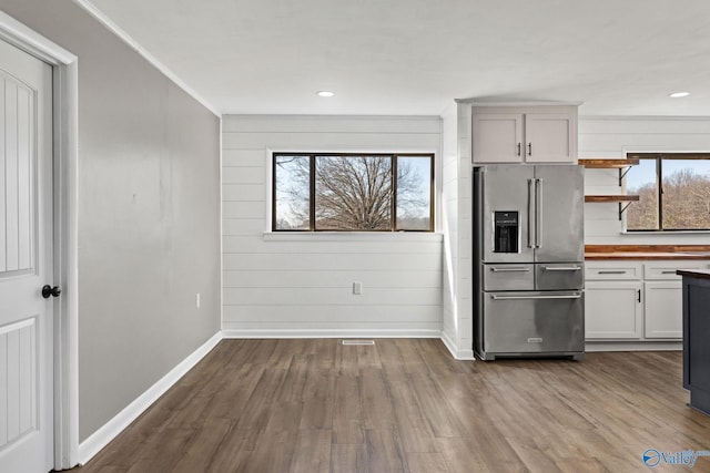 kitchen featuring high end refrigerator, white cabinets, a healthy amount of sunlight, and wood-type flooring