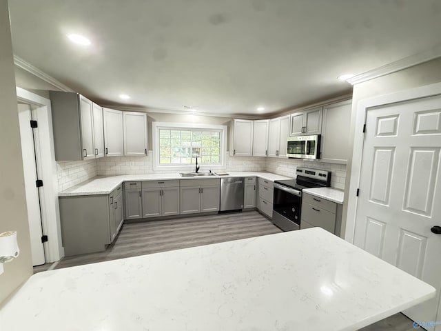 403 SW Arcadia St, Hartselle, AL 35640 - kitchen with gray cabinetry, stainless steel appliances, crown molding, light wood-type flooring, and a sink