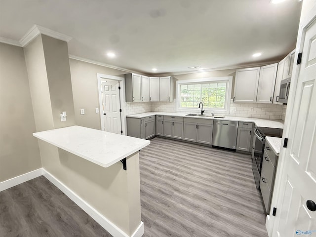 403 SW Arcadia St, Hartselle, AL 35640 - kitchen with gray cabinetry, stainless steel appliances, a sink, ornamental molding, and wood finished floors