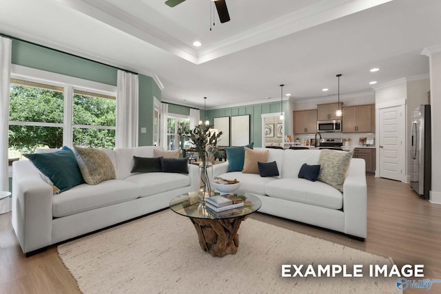 living room featuring ceiling fan, ornamental molding, and light wood-type flooring