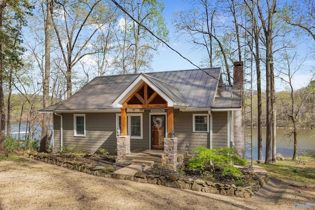 view of front of property featuring a chimney, covered porch, a water view, and metal roof