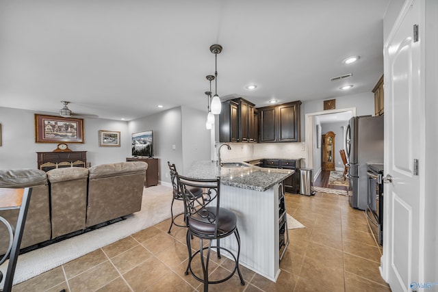 kitchen featuring sink, hanging light fixtures, stainless steel appliances, dark brown cabinetry, and kitchen peninsula