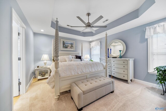 carpeted bedroom featuring a raised ceiling and ceiling fan